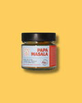 Glas Papa Masala Gewürzmischung von Karma Food auf gelbem Hintergrund. Perfekt für Currys, Eintopfgerichte, Omeletts und bunte Gemüse Bowls, nach traditionellem Familienrezept