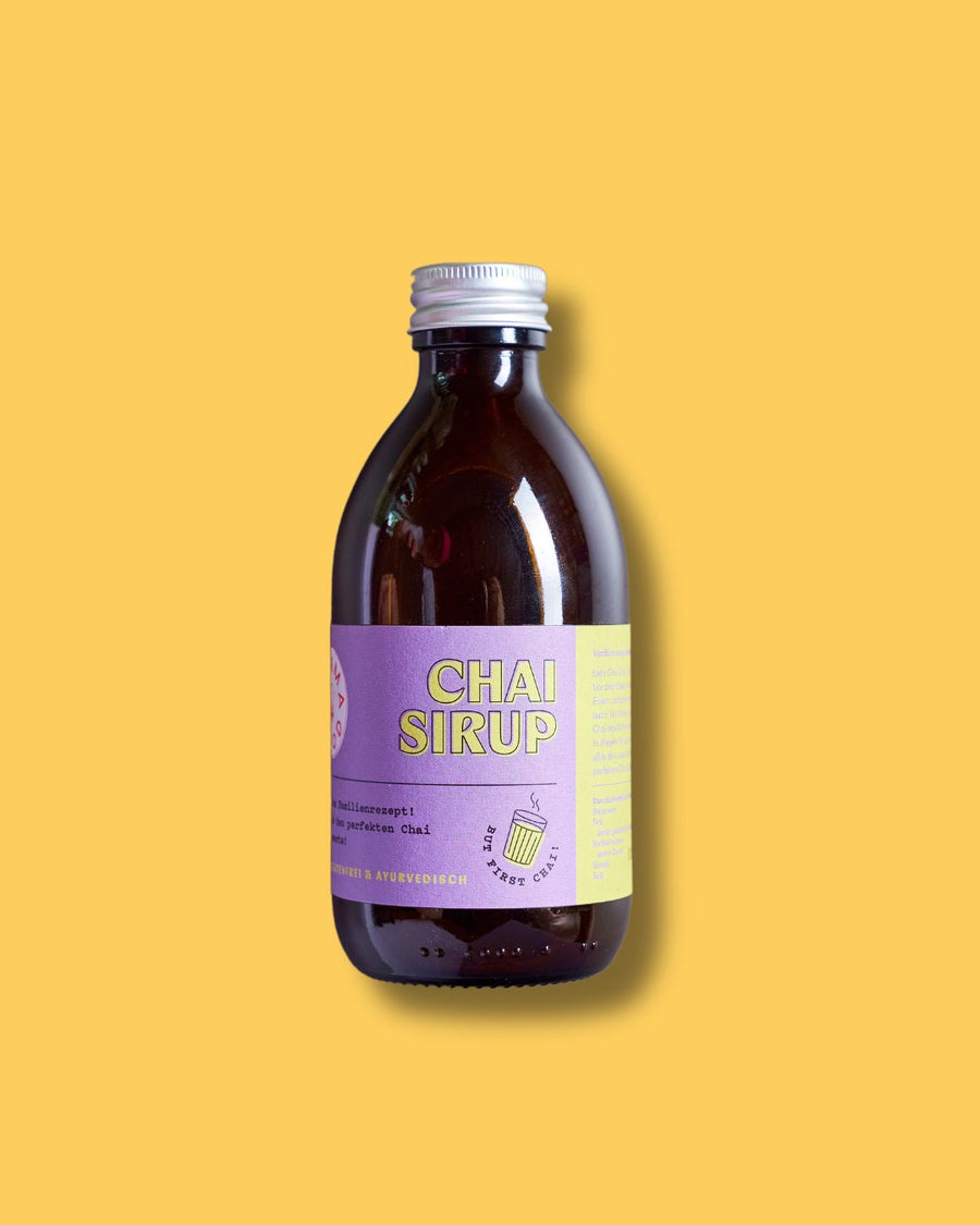Braune Flasche Karma Food ayurvedischer Chai Sirup mit lila Etikett auf gelbem Hintergrund