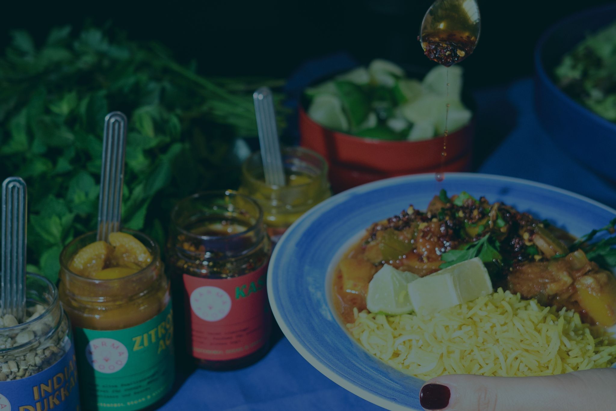 Indisches Curry mit gelbem Reis, frischem Koriander und Zitronenstück, serviert mit Karma Food Kashmiri Chili Crisp, Zitronenpaste und Curry im Glas – authentischer Genuss wie in Indien, schnell zubereitet mit Karma Food