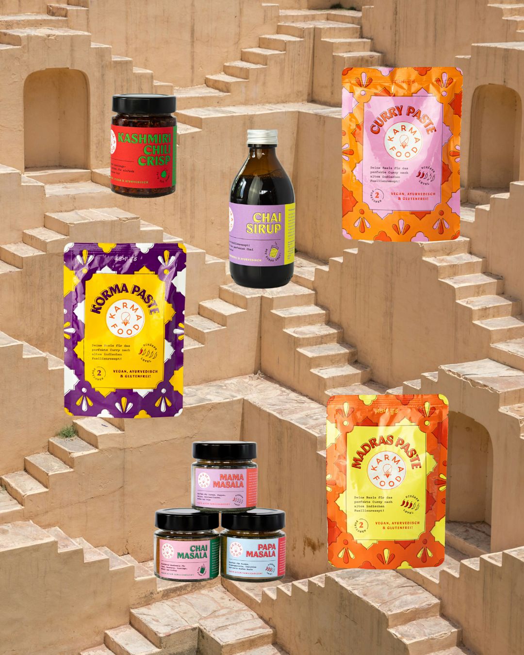 Karma Food Curry Party Starter Set mit Chai Sirup, Kashmiri Chili Crisp, Korma-, Madras- und Curry-Pasten sowie Mama-, Papa- und Chai-Masala vor indischer Stufenarchitektur – vegane Gewürz- und Saucenvielfalt online kaufen