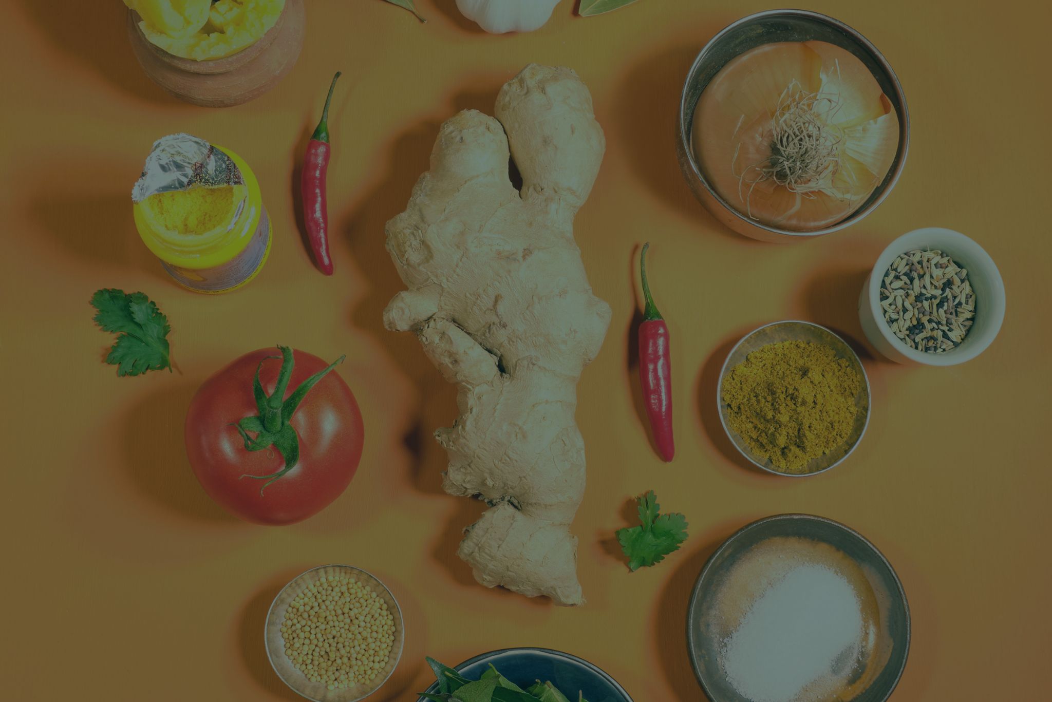 Frische Zutaten für indische Currys: Ingwer, Tomate, Zwiebel, Chili, Kurkuma, Ghee, Curry-Gewürz und Kräuter – Grundlage für Karma Food Curry Pasten und authentische indische Gerichte zuhause