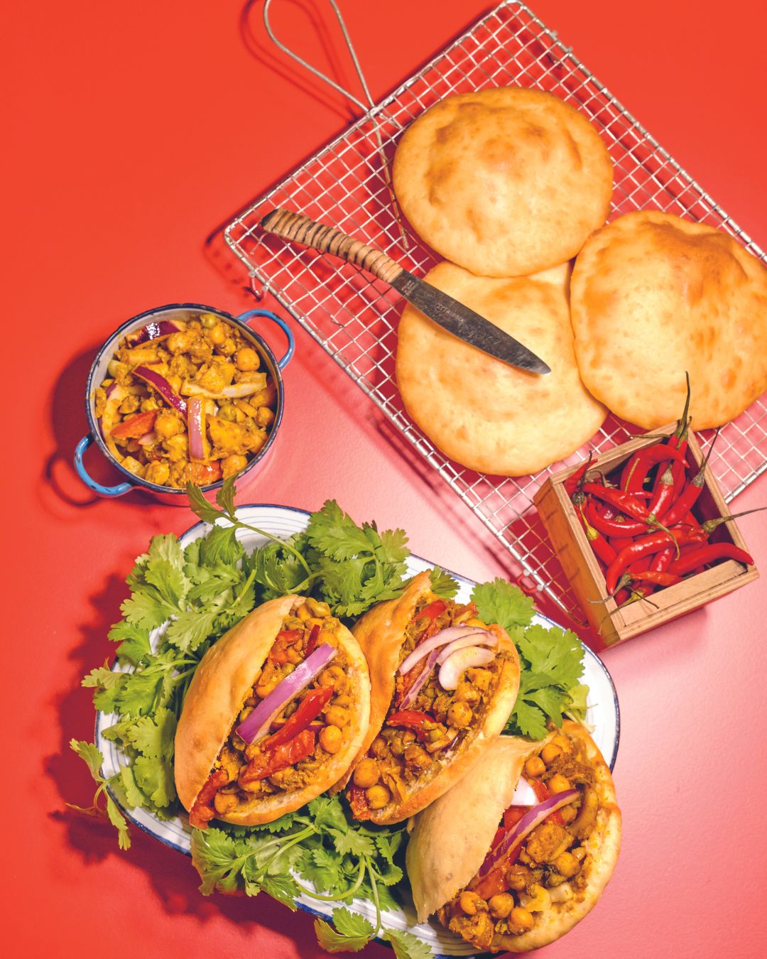 Indische Brottaschen gefüllt mit würzigem Kichererbsen-Curry, serviert mit frischen Kräutern und Naanbrot