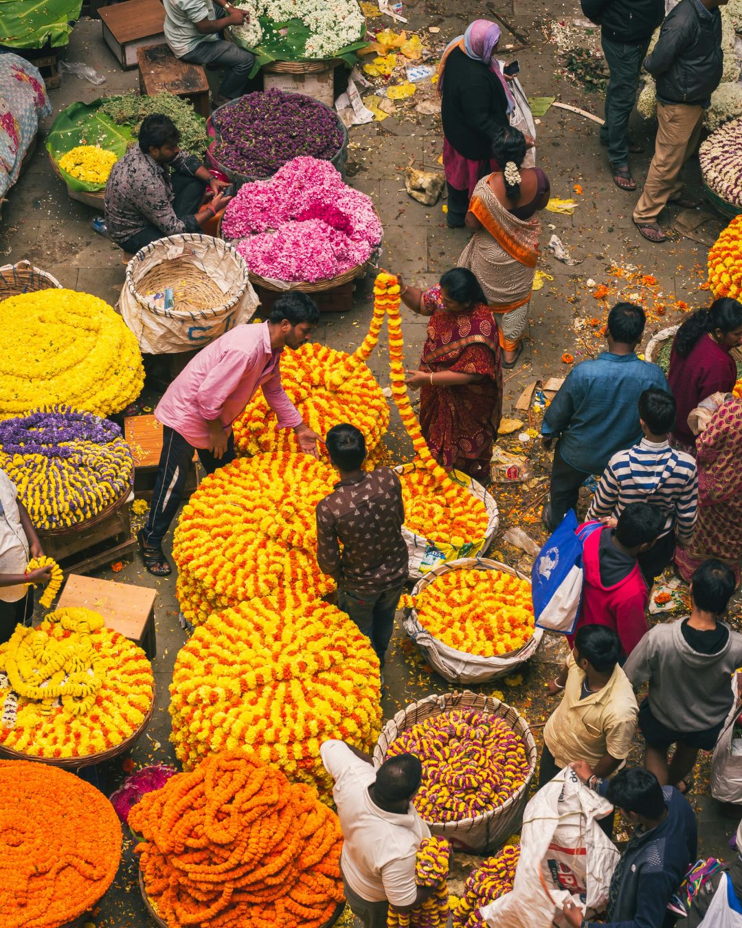 Bunter Blumenmarkt in Indien mit Menschen, die Blumengirlanden aus Ringelblumen und Jasmin verkaufen