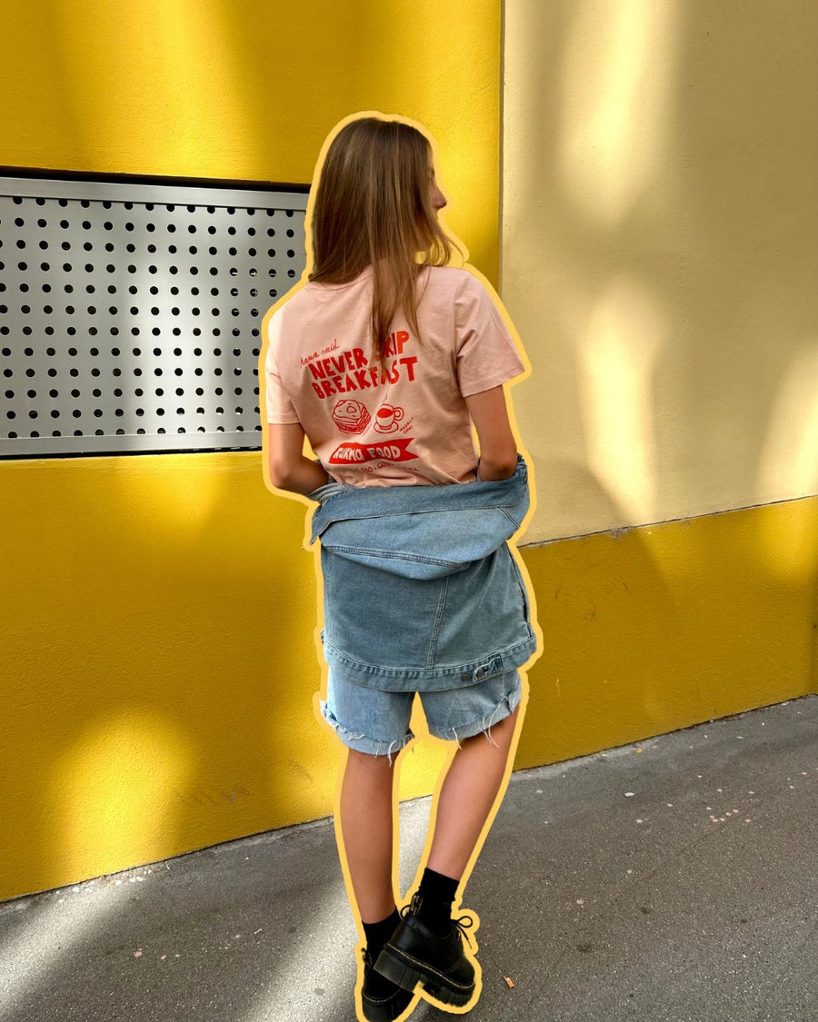 Karma Food T-Shirt in Rosa mit „Never Skip Breakfast“-Aufdruck auf dem Rücken, kombiniert mit Jeansshorts und urbanem Streetstyle-Look