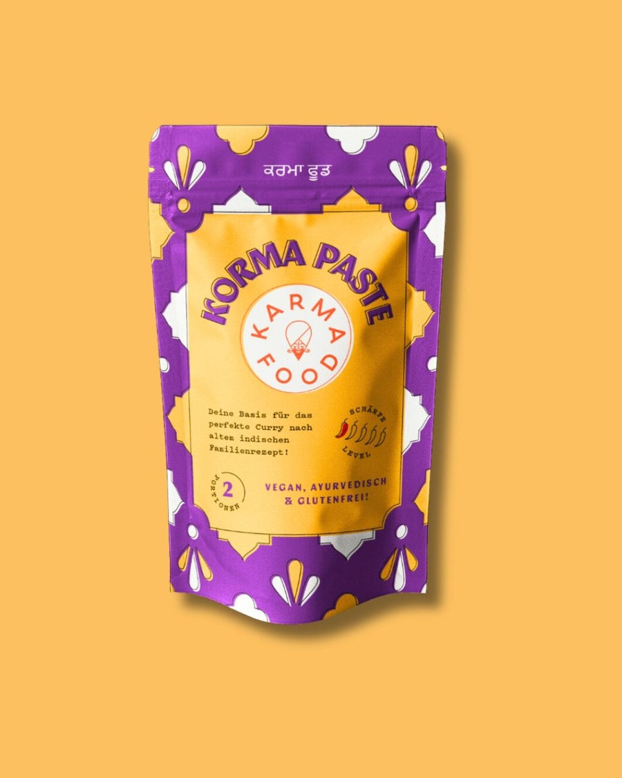 Einzelaufnahme der Korma Curry Paste von Karma Food auf gelbem Hintergrund, vegan und glutenfrei