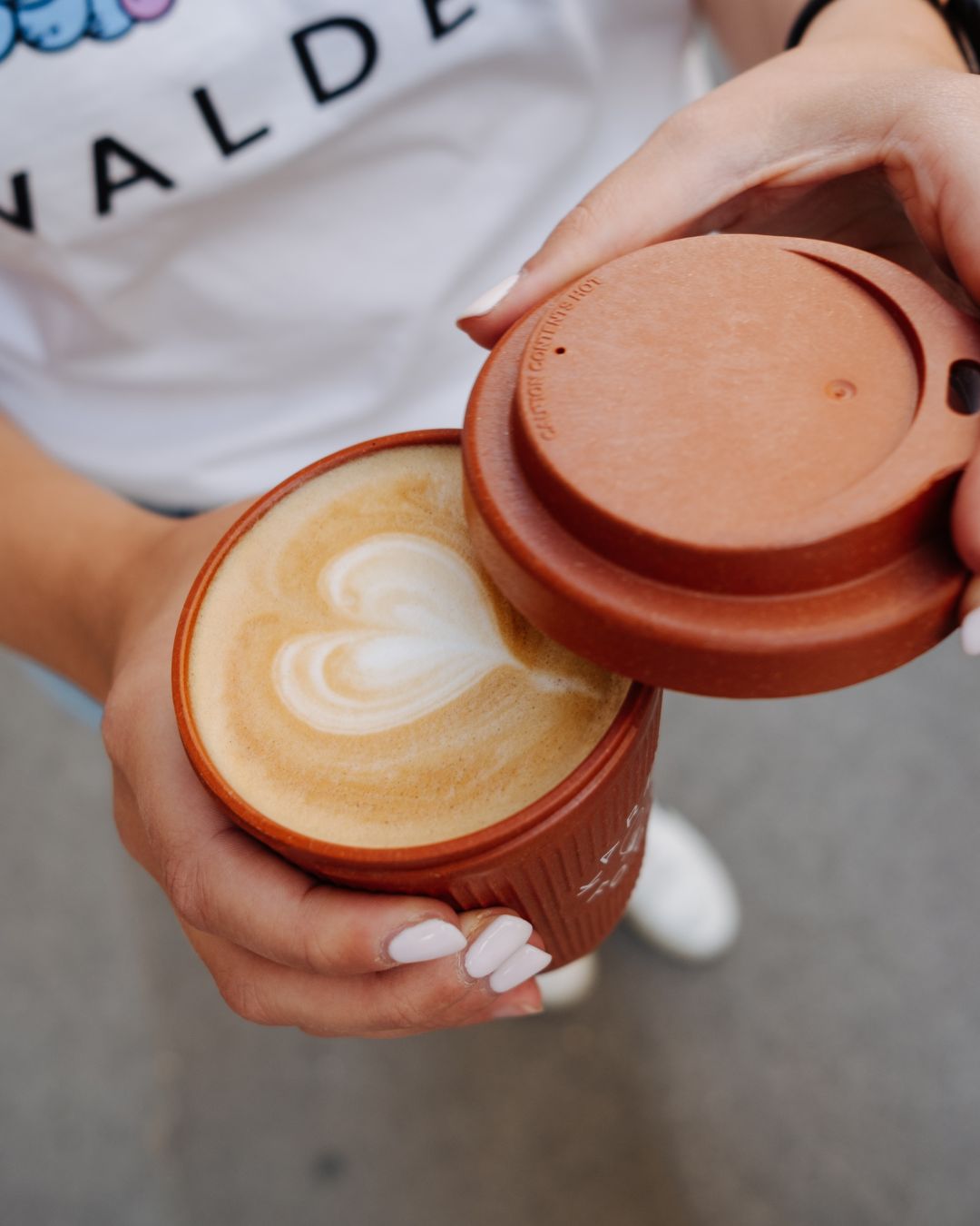 Latte mit Herz-Latte-Art im Weducer Cup von Karma Food, kurz bevor der Deckel aufgesetzt wird
