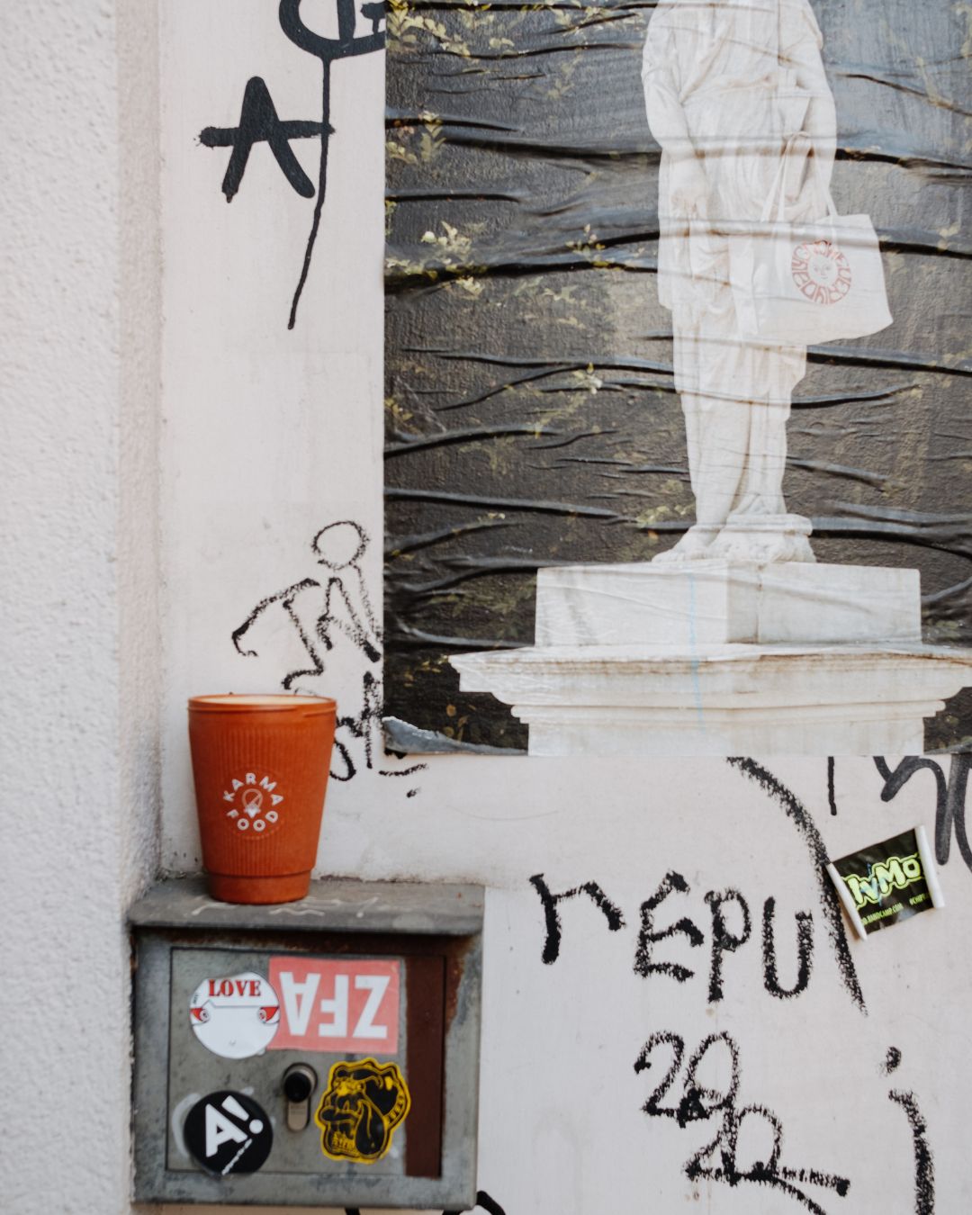 Weducer Cup von Karma Food vor urbaner Streetart-Wand mit Graffiti und Statue